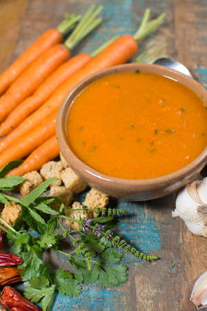 Spicy carrot soup with harissa made from hot chili pepper, lemon, garlic, coriander on blue wooden tableの写真素材