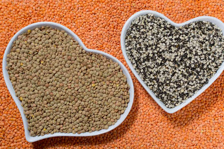 Heart form bowls with green and black  lentils over red lentils background - healthy food conceptの写真素材