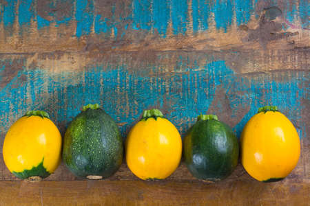 Round green and yellow courgette or zucchini, on wooden background, close up, healthy foodの写真素材