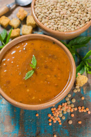 Homemade red lentils soup in old clay bowl with mintの写真素材