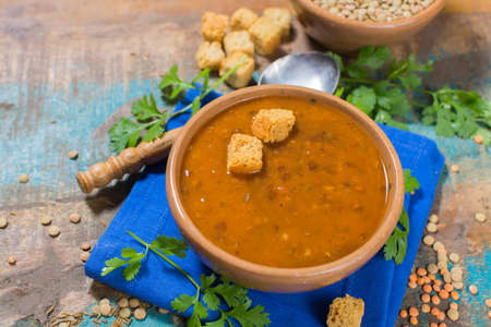 Homemade brown lentils soup in old clay bowl with green corianderの写真素材