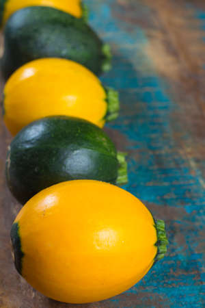 Round green and yellow courgette or zucchini, on wooden background, close up, healthy foodの写真素材