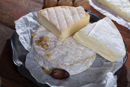Variety of French soft cheeses - camembert, marcaire, munster, brie - delicious dessert with nuts and dried fruitsの写真素材