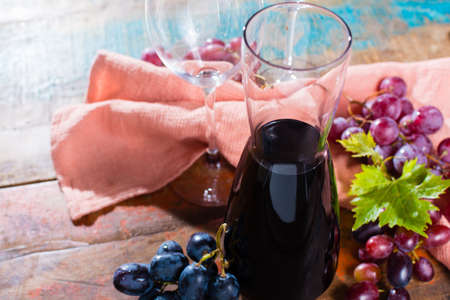 Small carafe with dry red wine, two wine glasses and grapes on the tableの写真素材