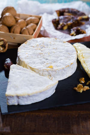 Variety of French soft cheeses - camembert, marcaire, munster, brie - delicious dessert with nuts and dried fruitsの写真素材