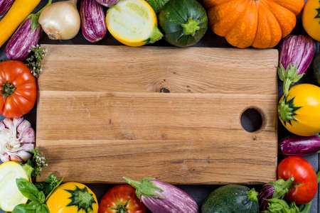 Wooden plate with copy space, restautant concept with fresh colorful organic vegetables - round courgette, small eggplants, tomatoes, diet concept, Italian and French food, healthy food. Menu temptale.の写真素材