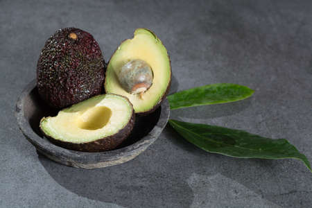 Ripe avocado with leaves close up on gray concrete background, diet and healthy food concept, copy spaceの写真素材