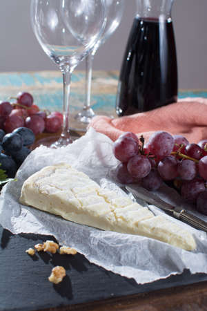 Famous French soft cheese - brie - delicious dessert with nuts, grapes, dried fruits and red wineの写真素材