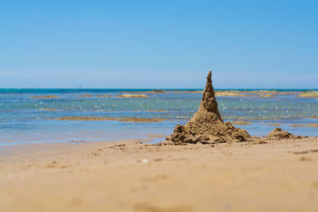 Sand castle on the beach with crystal blue sea waterの写真素材