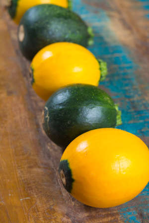 Round green and yellow courgette or zucchini, on wooden background, close up, healthy foodの写真素材