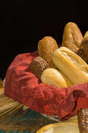 Variety of fresh baked wheat and rye bread, baguette and buns with wheat ears