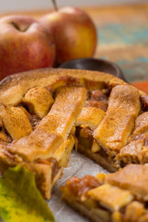Traditional homemade apple pie with nuts and cinnamon close up and fresh ripe Golden Reinette apples on wooden tableの写真素材