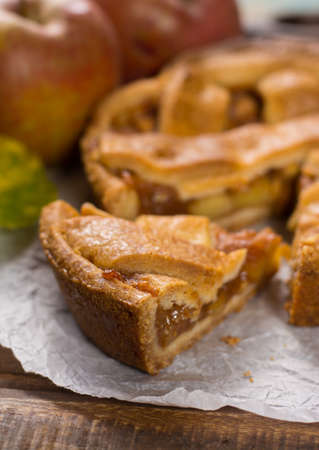 Traditional homemade apple pie with nuts and cinnamon close up and fresh ripe Golden Reinette apples on wooden tableの写真素材