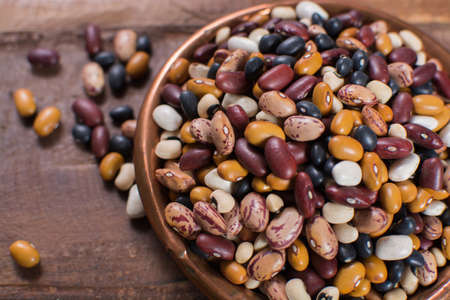 Variety of protein rich colorful raw dried beans on wooden tableの写真素材