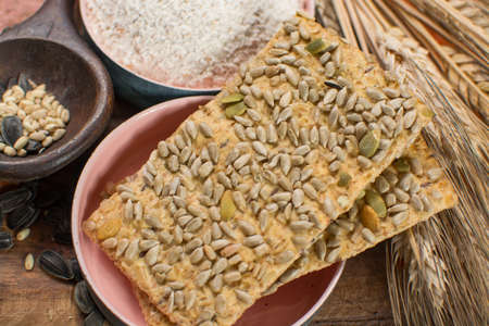 Whole grain wheat flour, sunflowers seeds and healthy fresh baked crackers close upの写真素材