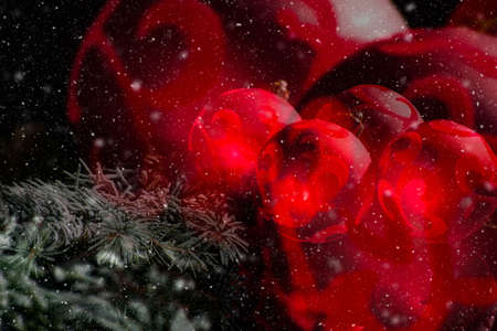 Abstract red christmas tree decoration, red balls with ornament and green fir on black background with snow and reflection close up copy spaceの写真素材