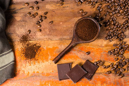 Dark roasted pure arabica coffee beans and ground coffe in old spoon on the wooden table, copy spaceの写真素材