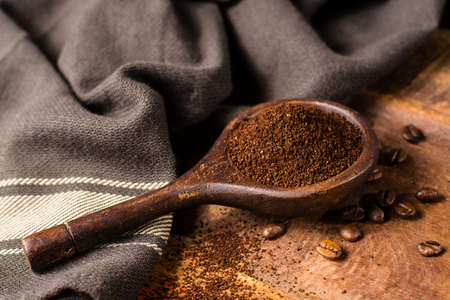 Dark roasted pure arabica coffee beans and ground coffe in old spoon on the wooden table, copy spaceの写真素材