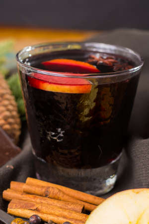 Warm mulled wine for Christmas days, prepared with apple, orange and spices on wooden table with Christmas decorationの写真素材