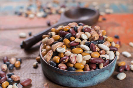 Variety of protein rich colorful raw dried beans on wooden tableの写真素材