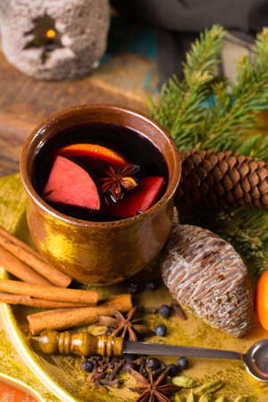 Warm mulled wine for Christmas days, prepared with apple, orange and spices on wooden table with Christmas decorationの写真素材
