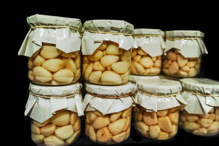 Pickled garlic cloves in glass jars on shelf in ond french shopの写真素材