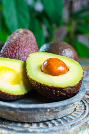 Healthy vegetarian food â green ripe avocado, new harvest, with leaves on stone plates with ornament close upの写真素材