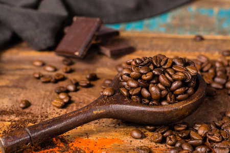 Dark roasted pure arabica coffee beans and ground coffee in old spoon on the wooden table, copy spaceの写真素材
