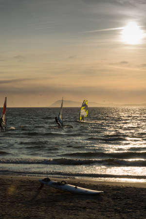 Sunset over the sea or ocean and extreme freestyle sport windsurfing school, France, Giens