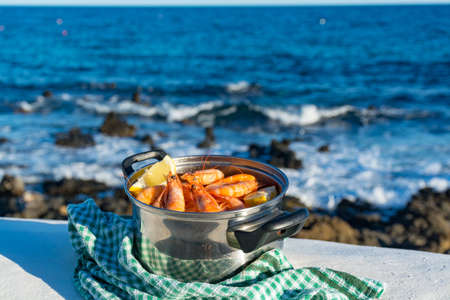 Fishermen village, fresh cooked prawns, shrimps in steel pan served outside with lemon, sea viewの写真素材