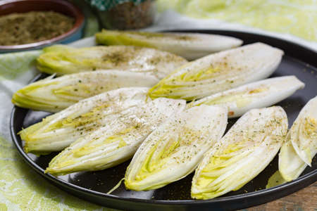 Fresh raw Belgian bitter chicory salad ready to cook with herbs and olive oil, close upの写真素材