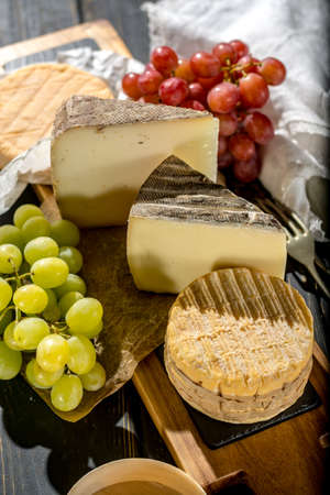 Tasting of oldest french AOC soft pudgent yellow cheese Livarot, Munster and semifirm Tomme, made...
