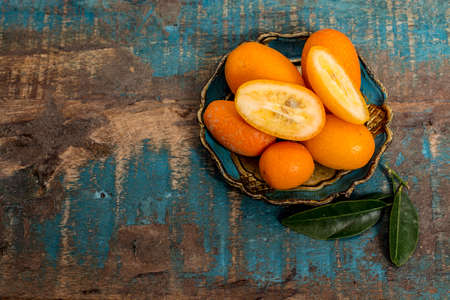 Delicious small citrus fruits orange kumquats close up on wooden table