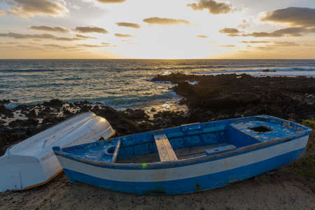 Sunset over the sea landscape with old blue wooden fishing boatの写真素材