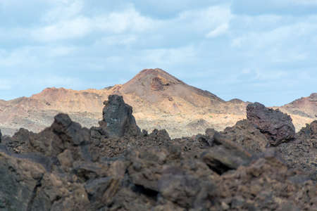 Views on black lava mountains during guided hiking discovery tour Termesana route in Timanfaya national park, Lanzarote, Canary, Spain.の写真素材