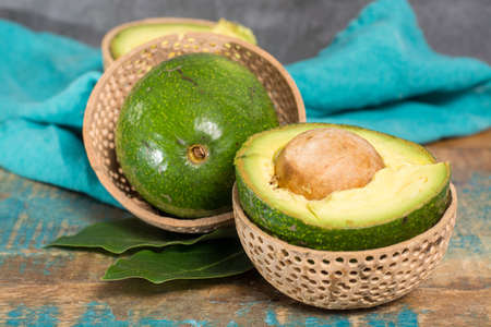 Green ripe tasty Ryan avocado with big round seed, ready to eat on wooden table.