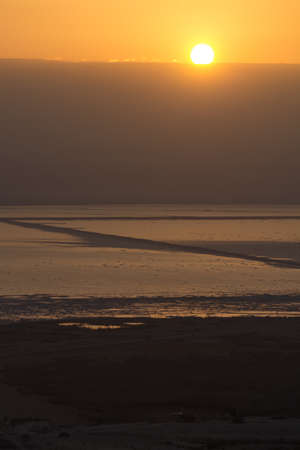 Sunrise over lowest salty lake in world below sea level Dead sea, full of minerals near luxury vacation resort Ein Bokek, perfect place for medical treatments, climatotherapy, thalassotherapy and heliotherapy.の写真素材