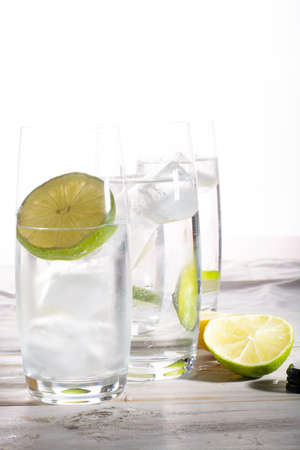 Stil mineral drink water in glass bottle served with three glasses with ice cubed, lime and lemonの写真素材