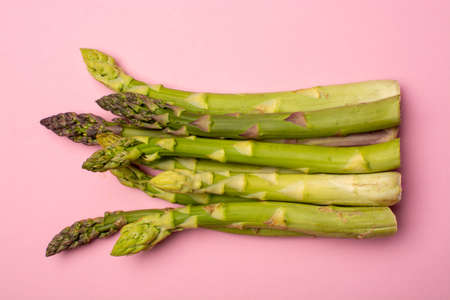 Delicious bunch of raw ripe green asparagus new harvest isolated on trendy pink background flat lay food conceptの写真素材