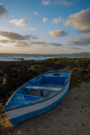 Sunset over the sea landscape with old blue wooden fishing boatの写真素材