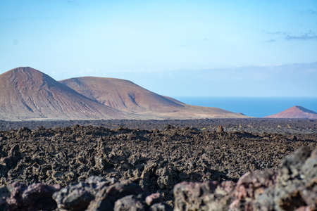 Views on black lava mountains during guided hiking discovery tour Termesana route in Timanfaya national park, Lanzarote, Canary, Spain.の写真素材