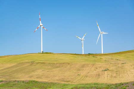 Modern wind farm with big wind turbines towers, source for renewable green energyの写真素材