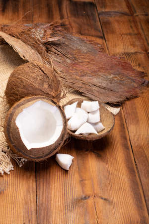Big tropical palm nut coconut and coconut pieces ready to eat on wooden background close upの写真素材