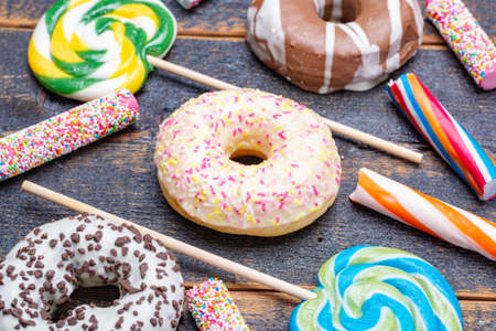 Children party background with sweet colorful donuts and candy close up on wooden tableの写真素材