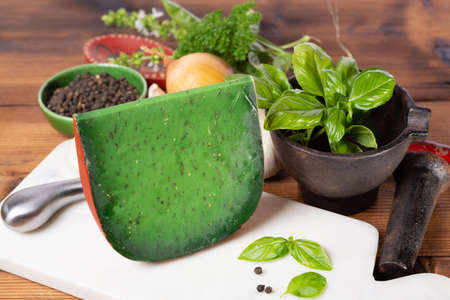 Piece of green pesto hard Dutch cheese made with fresh basil herb, garlic and onion, close upの写真素材
