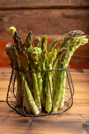 Delicious bunch of raw ripe green asparagus new harvest on wooden backgroundの写真素材