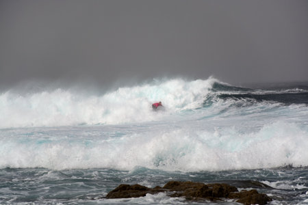 Storm in Atlantic ocean, one surfer man on big dark stormy water wavesのeditorial素材