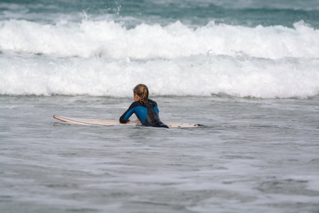Undefined surfers with surf boards in water of Atlantic ocean, winter on Lanzarote island, Famara...