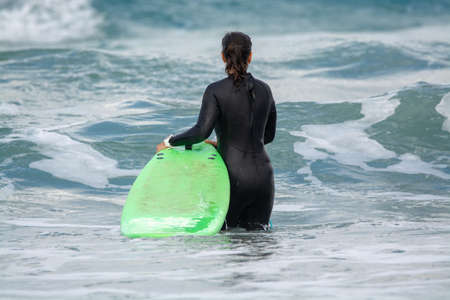 Undefined surfers with surf boards in water of Atlantic ocean, winter on Lanzarote island, Famara...
