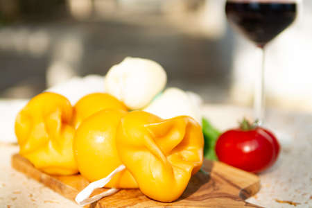 Smoked and white Fresh South Italian traditional cow or cow and sheep semi-soft cheese Scamorza served outdoor on olive wood boardの写真素材